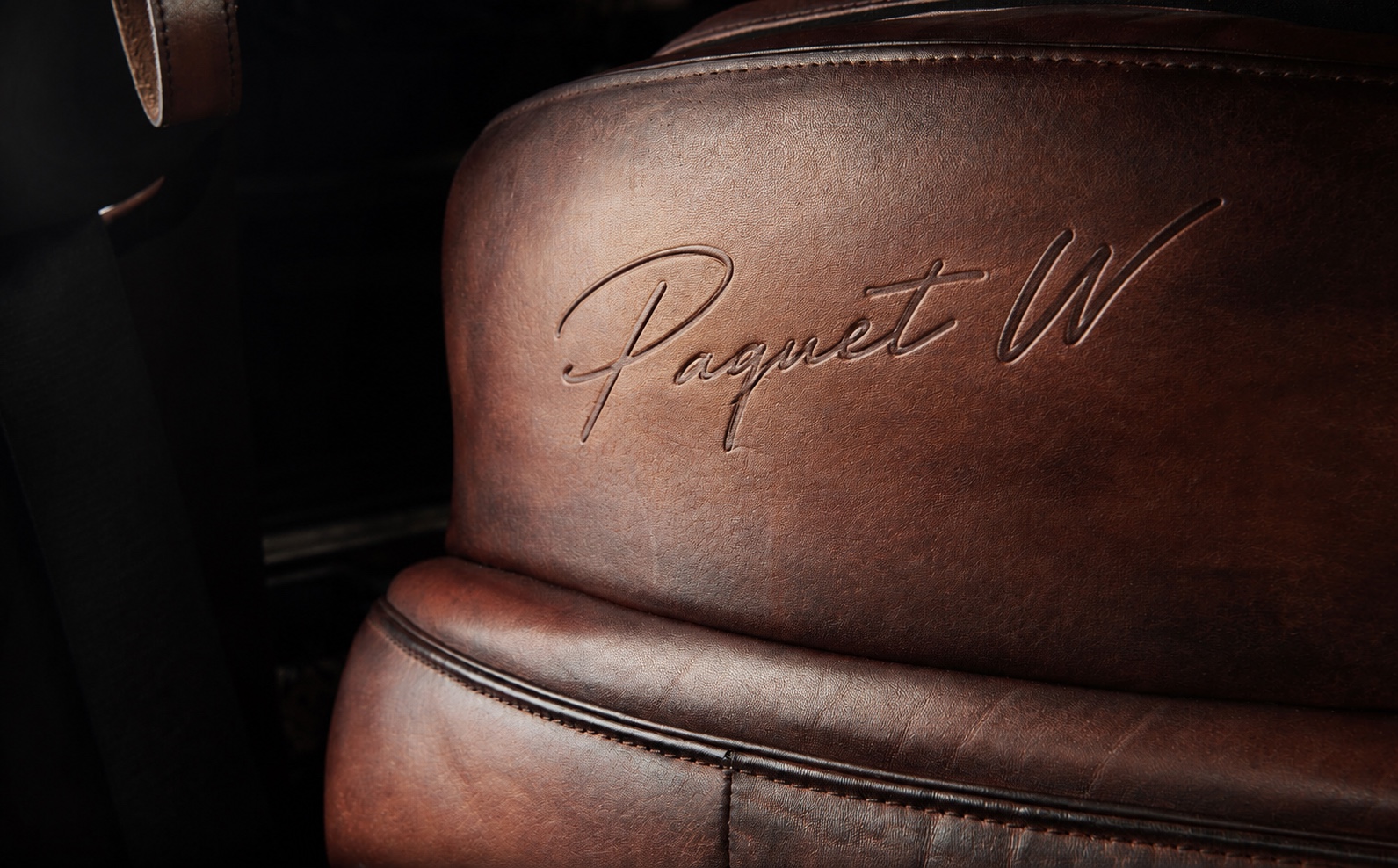 Signature Paquet W embossée dans un cuir automobile cognac